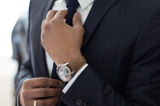 Close up of chest and hands of a man adjusting his tie on a suit he is wearing to an interview