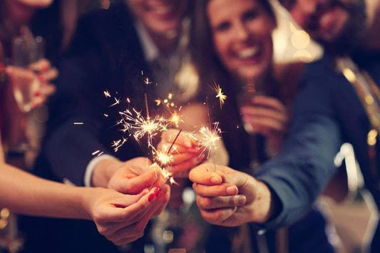 Group of friends holding sparklers close to camera on a fireworks night party - style tips on how to look good on bonfire night